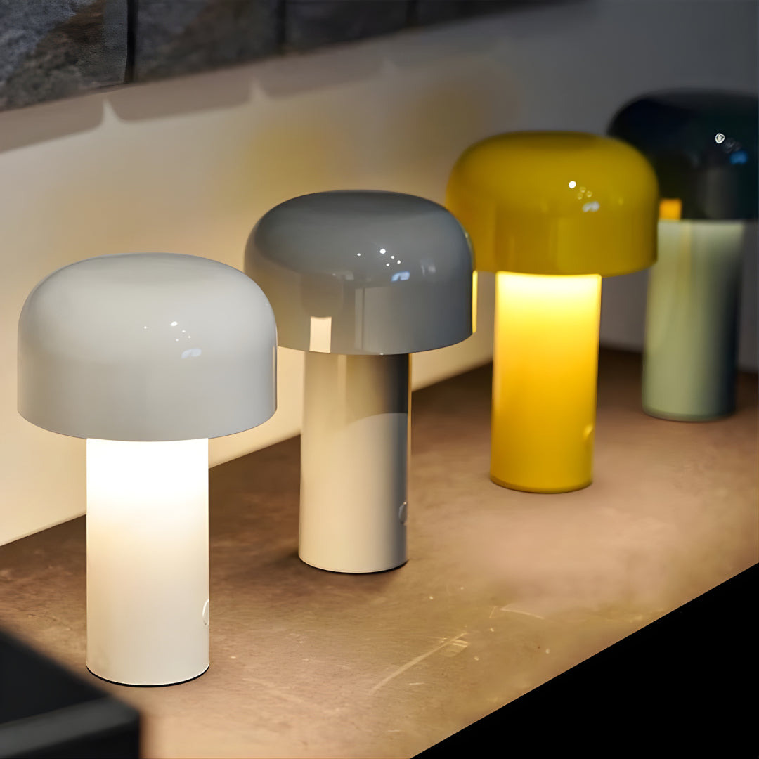 Three mushroom-shaped lamps in different colors on a wooden surface.