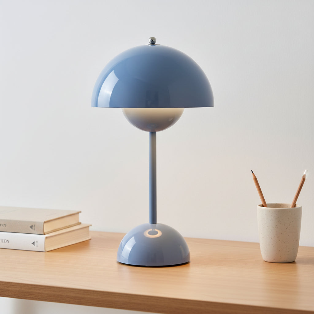 Blue table lamp on a wooden surface with books and a cup in the background