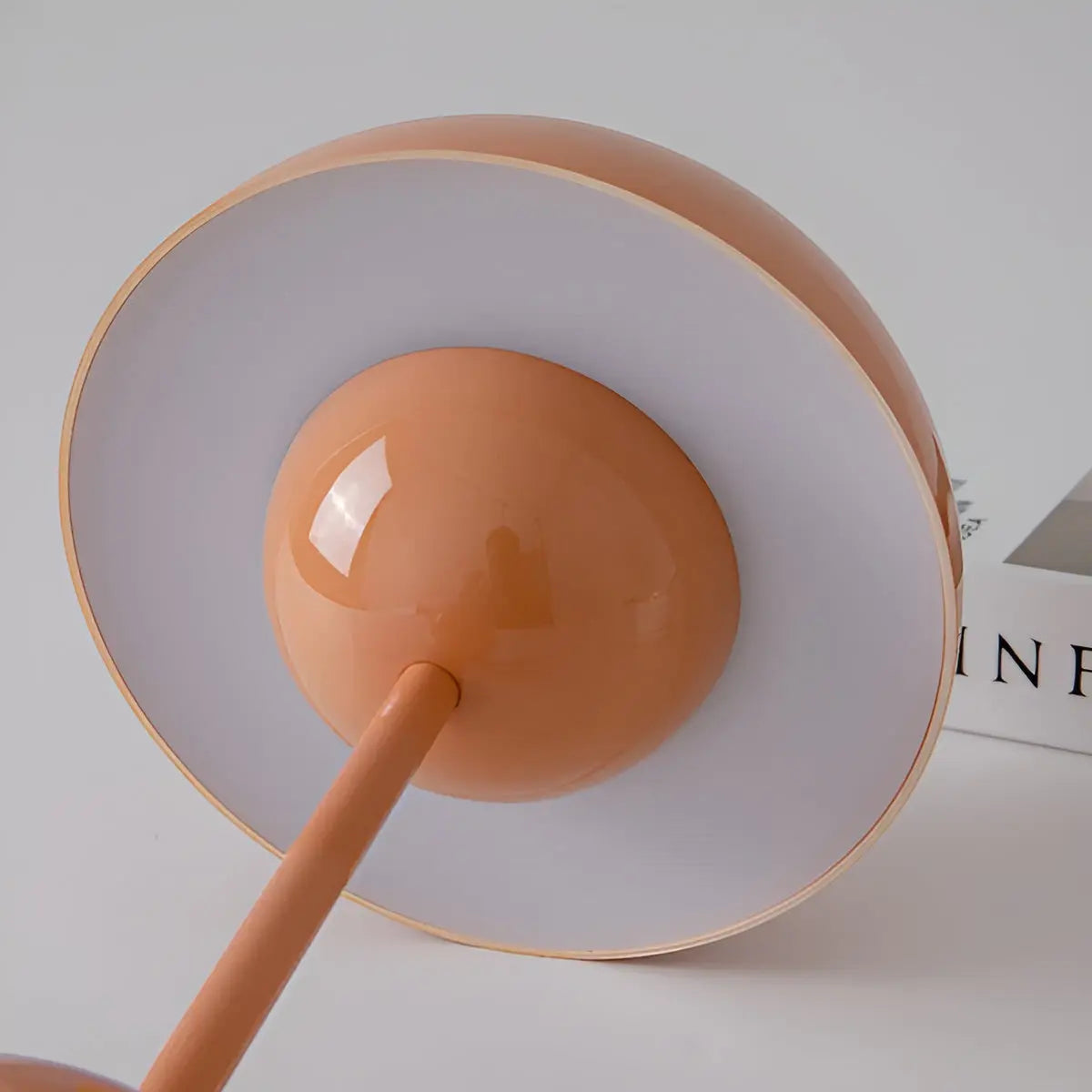 Close-up of a lamp with a peach-colored shade and base on a light gray background.