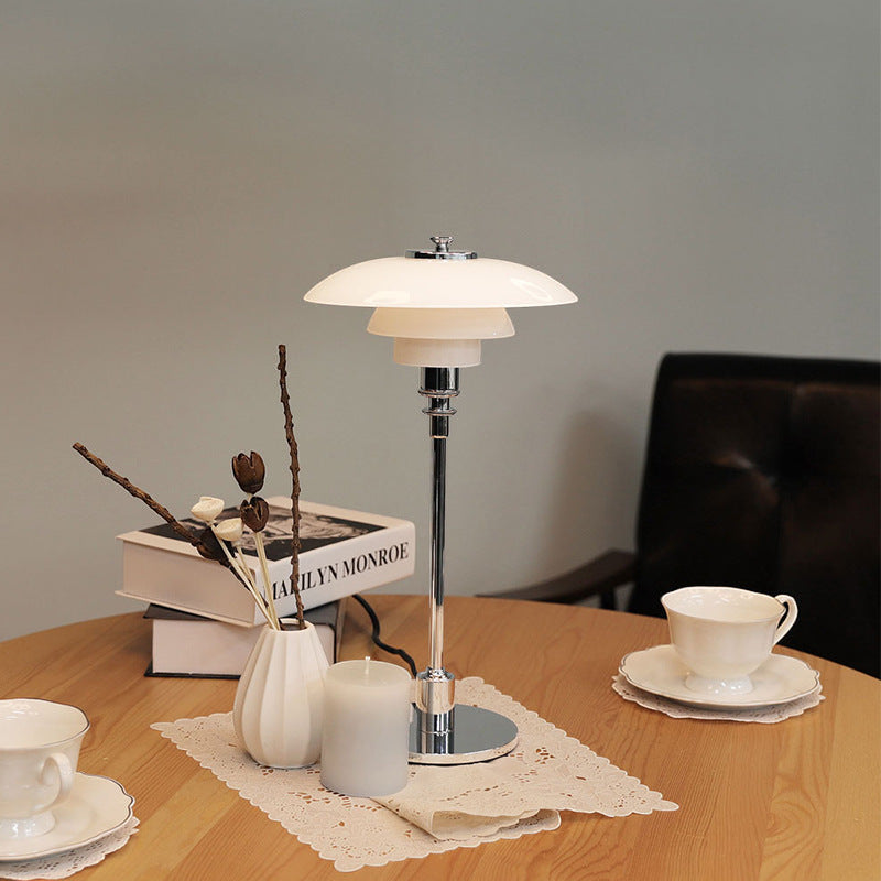 Table lamp on a wooden table with decorative items including books and a cup.