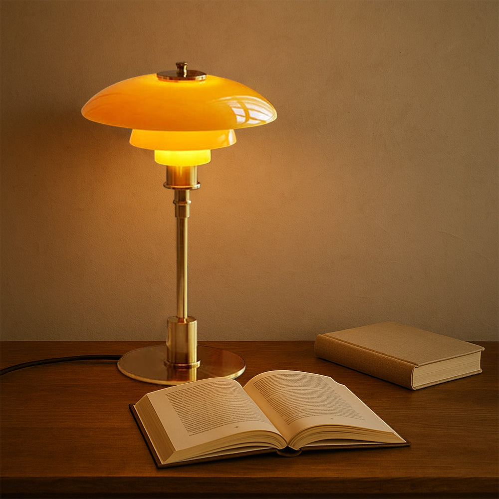 Yellow table lamp on a wooden surface with an open book next to it, against a beige wall.