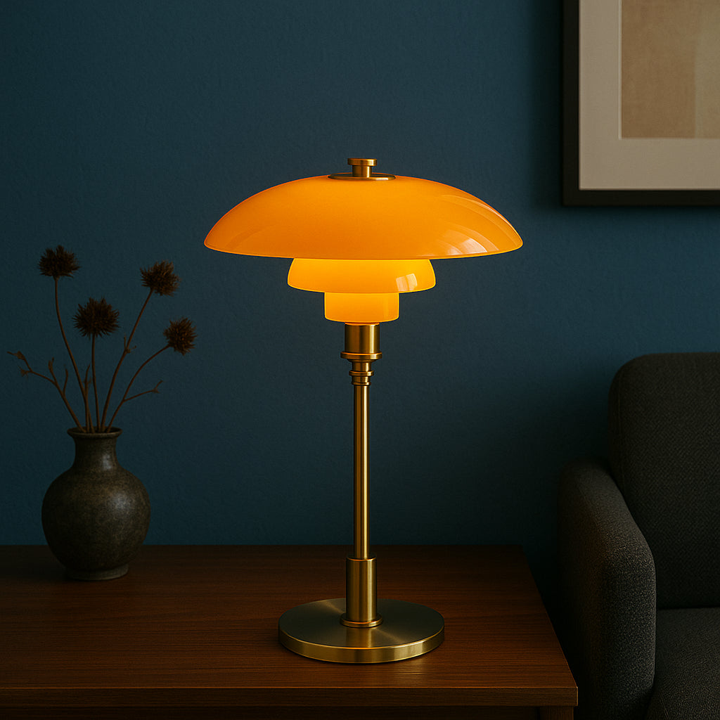 Orange table lamp with gold base on a wooden surface against a dark blue wall.