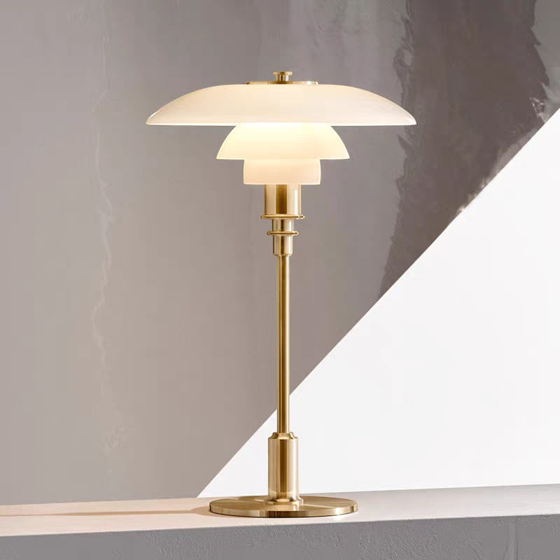 Gold table lamp with white glass shade on a gray background
