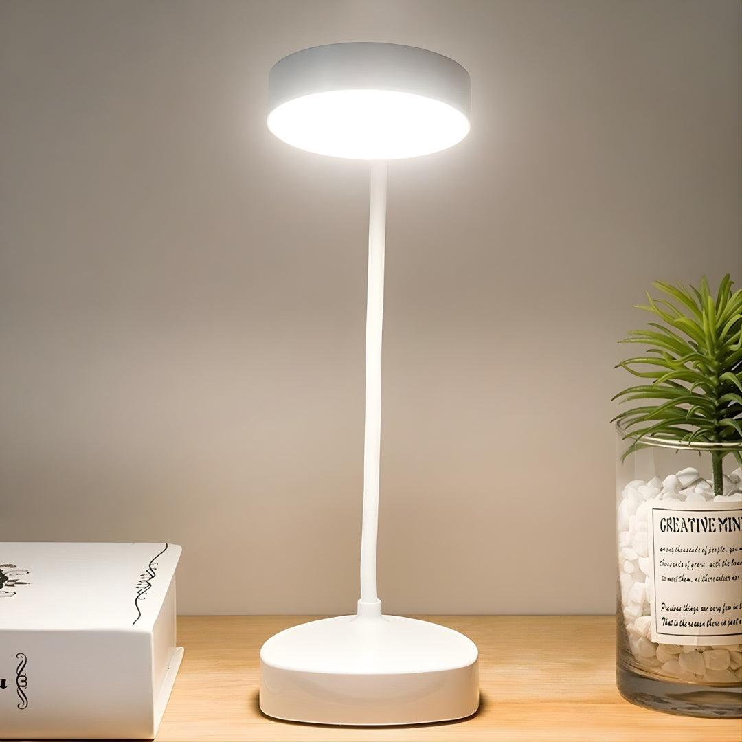 White LED desk lamp on a wooden surface with a plant and book in the background