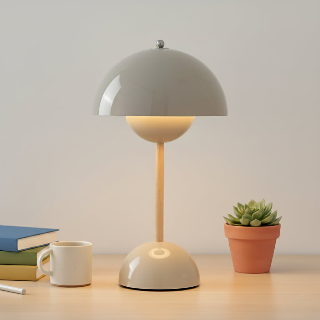 Table lamp on a desk with books and a plant in the background