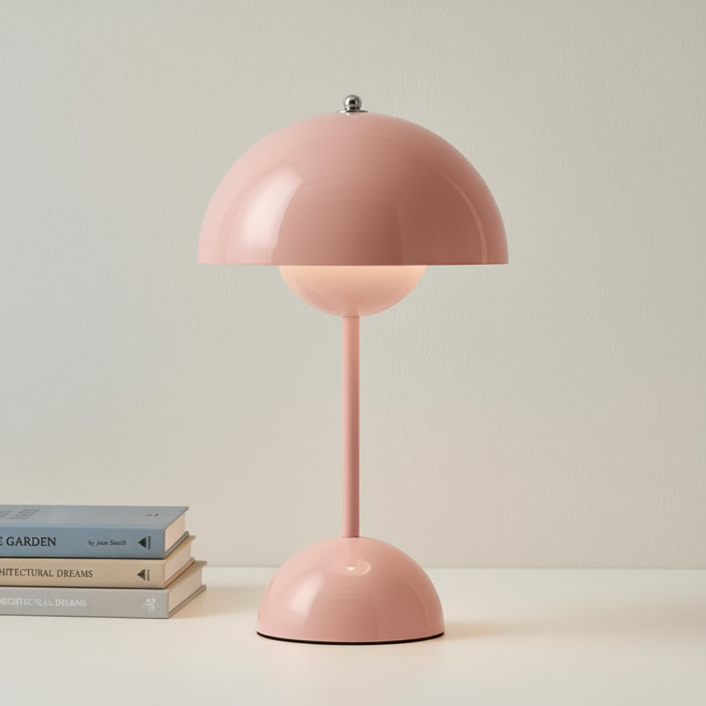 Pink table lamp on a light surface with books in the background